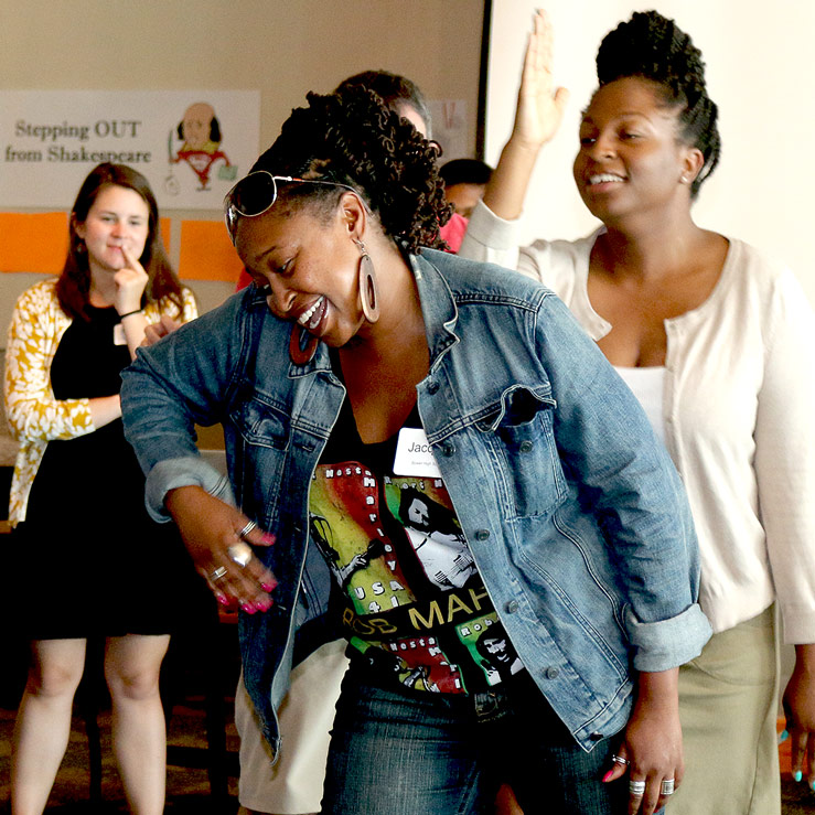 Group of people participating in a joyful activity, with a woman in the foreground smiling and bending forward.