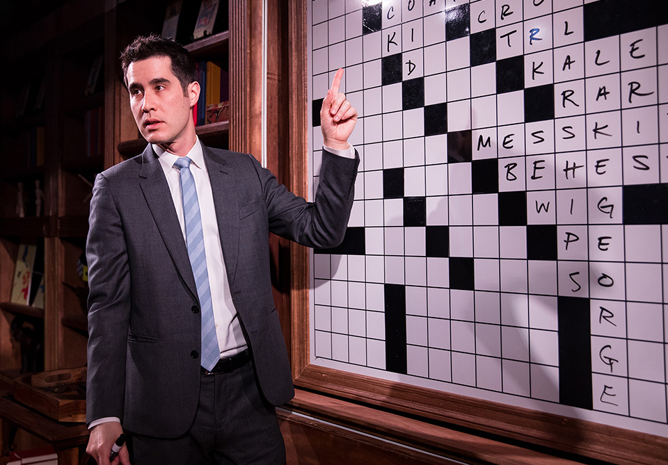 David Kwong in front of enlarged crossword on board