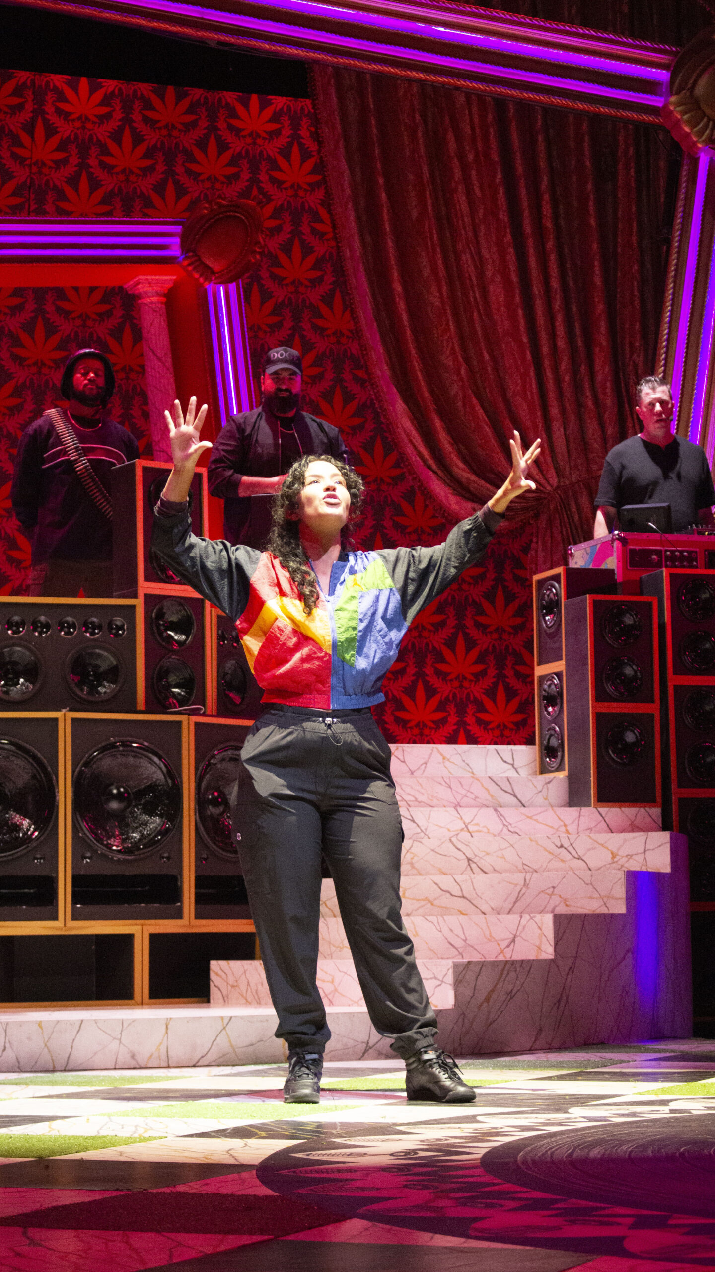 A woman on a stage with a colorful jumper and several people behind her 