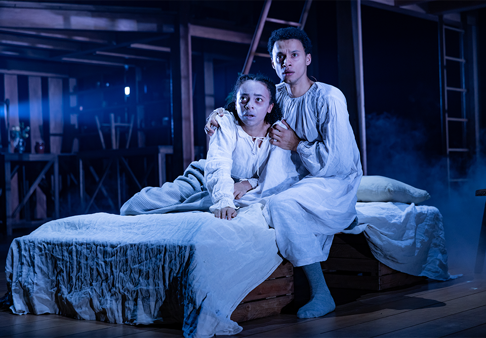 two children in a bed on a stage looking sickly and colorless