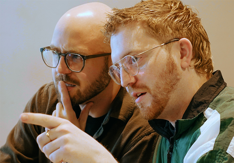 Two individuals with glasses engaged in a focused conversation.