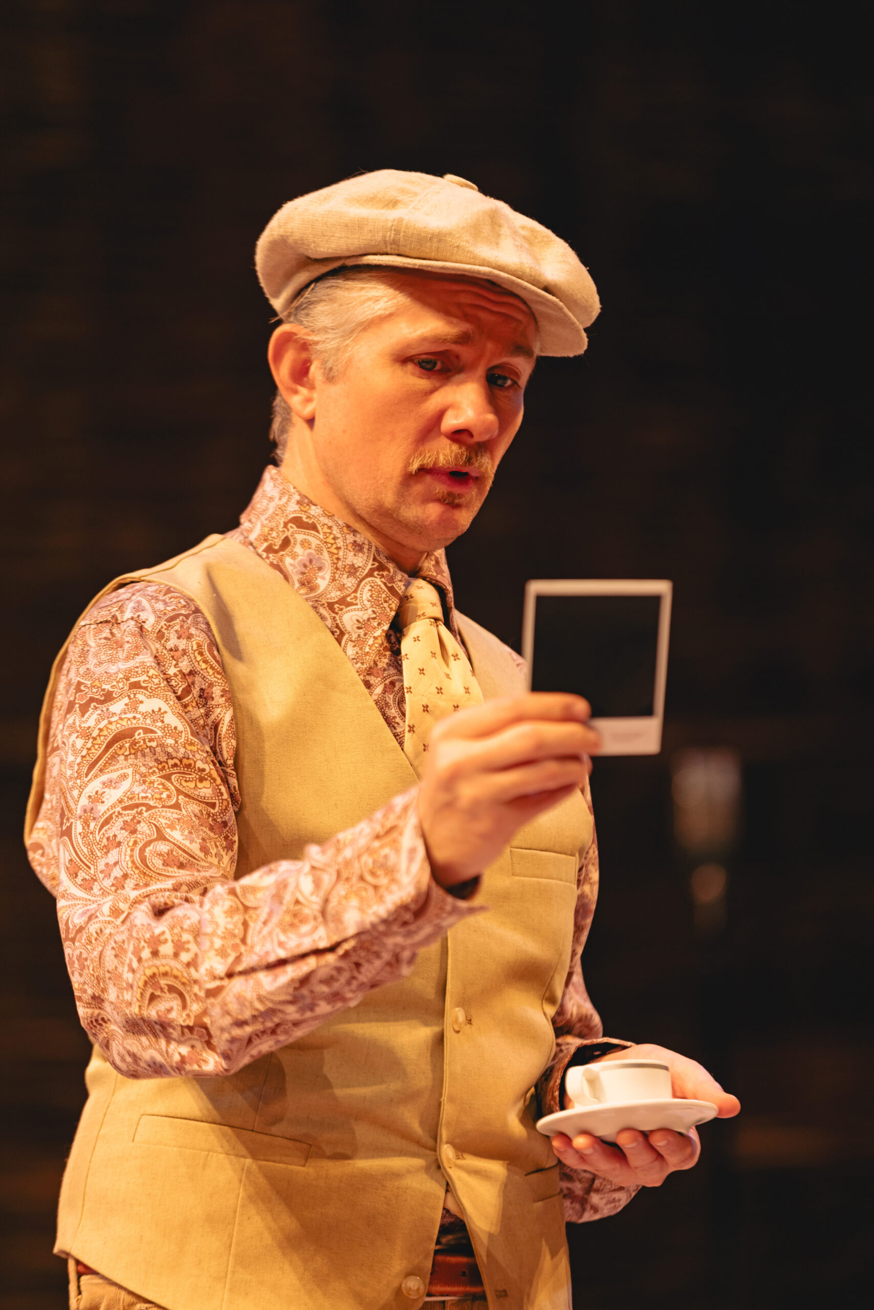 Actor Erik Hellman as character, Camillo looks down at a polaroid photo